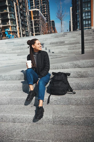 Joyous lady with a disposable paper coffee cup looking away — Stockfoto