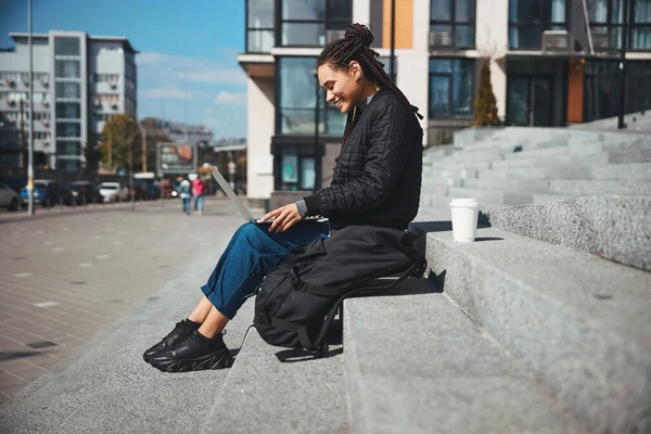 Leende dam med majskolvar som använder sin dator utanför — Stockfoto