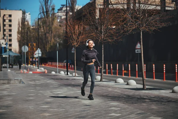 Pleased athletic woman jogging in the morning — Stock Photo, Image