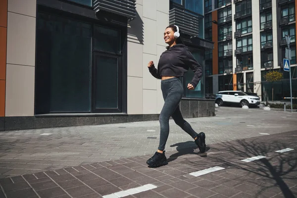 Joyous jogger i trådlösa hörlurar kör till musik — Stockfoto