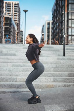 Afro sürüsü açık havada çömelmiş neşeli bir sporcu.