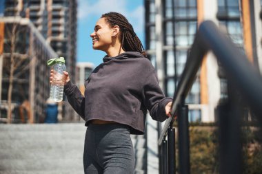 Elinde plastik su şişesi olan bir kadın mesafeye bakıyor.