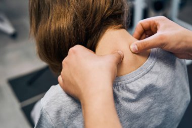 Üniformalı Osteopat, masaj yatağında genç bir bayanın boyun omurlarını düzenliyor.