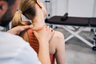 Physiotherapist hand massaging woman painful neck in physic room closeup back view. Recovery therapy