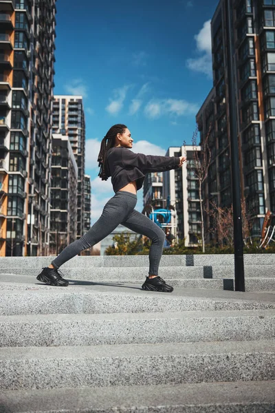 Leende sportig dam värmer upp på betongtrappan — Stockfoto