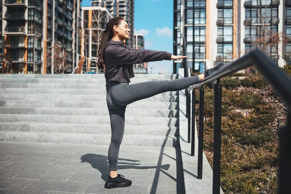 Pretty lady performing a stretching exercise using the handrail — Stock Fotó