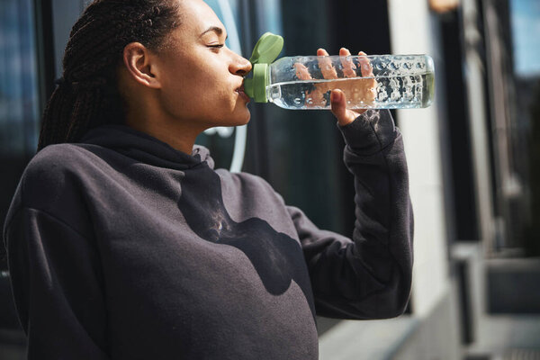 Calm woman dressed in a sweatshirt restoring her fluid balance