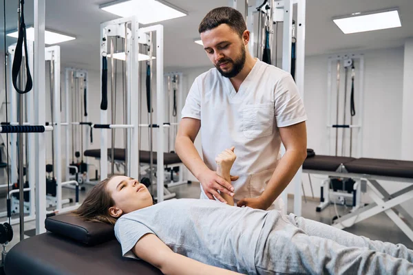 Portret van fysiotherapeut massages meisjes hand in fysiokamer. Professionele pediatrische therapeut — Stockfoto