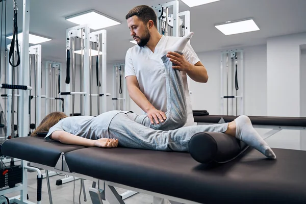 Фізіотерапевт контролює коліно пацієнта в яскравій реабілітаційній клініці крупним планом. масажист — стокове фото