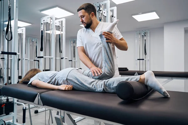 Physiotherapist controlling knee of patient in bright rehab clinic closeup. Massage therapist — 스톡 사진