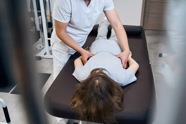 Professional manual therapist treats incorrect posture of girl lying on massage bed. Physiotherapist — Foto de Stock