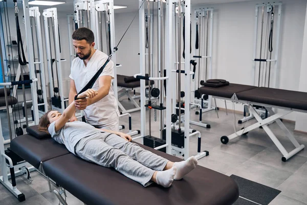 Physiotherapist treats girl in rehabilitation center on elastic machines. Chiropractor treatments — 스톡 사진