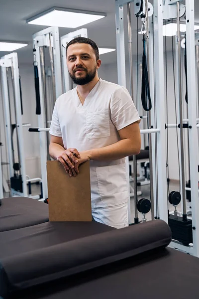 Portrait of bearded caucasian doctor with clipboard in hands.Serious confident professional masseur — Stock Fotó