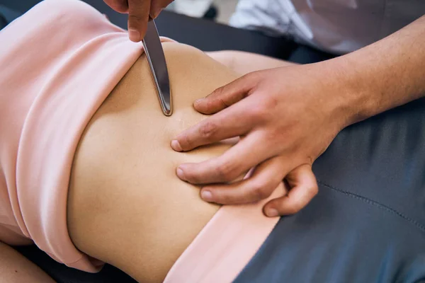 Physiotherapist checks woman abdominal muscles on massage bed. Therapeutic IASTM treatment session — 스톡 사진