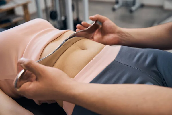 Chiropractor massages vrouw met behulp van IASTM hulpmiddel voor het schrapen van spieren in rehab clinic gym closeup — Stockfoto