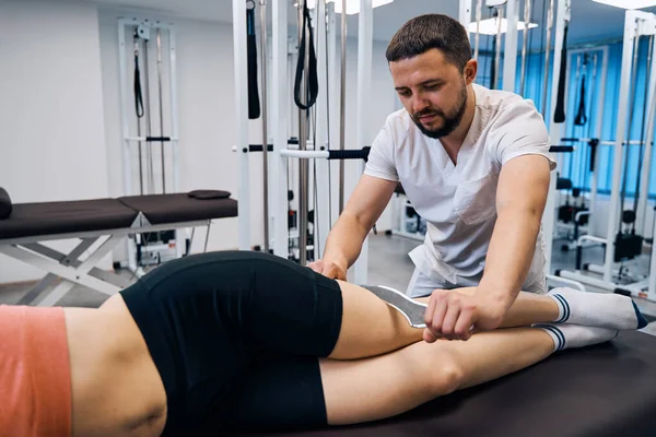 Fysiotherapeut masseert jonge vrouw met gereedschap. Masseur behandelt sport blessure met IASTM behandeling — Stockfoto