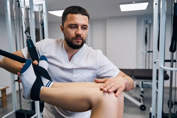 Allenamento di forza di gambe di giovane donna, ginocchio su simulatore flessibile nel centro di riabilitazione primo piano — Foto Stock