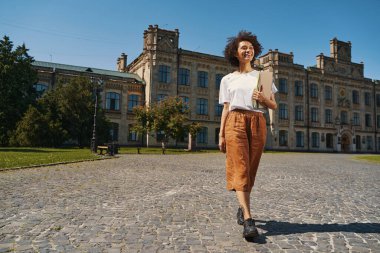 Mirthful young lady returning from the university