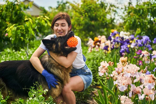 Happy female person playing with animal in yard — Stockfoto