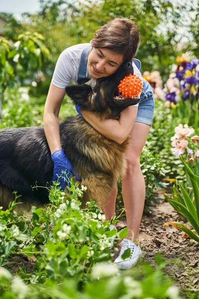 Cute housewife hugging dog and cleaning yard — Stockfoto