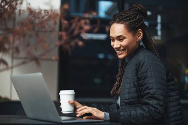 Mirthful lady working outdoors and drinking coffee