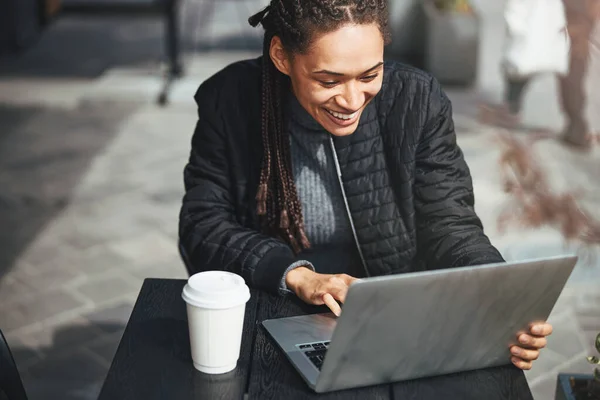 Щаслива жінка в теплий день сидить на відкритому повітрі з ноутбуком — стокове фото
