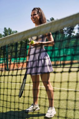 Sahada sevimli, koyu saçlı, neşeli sporcu kadın.