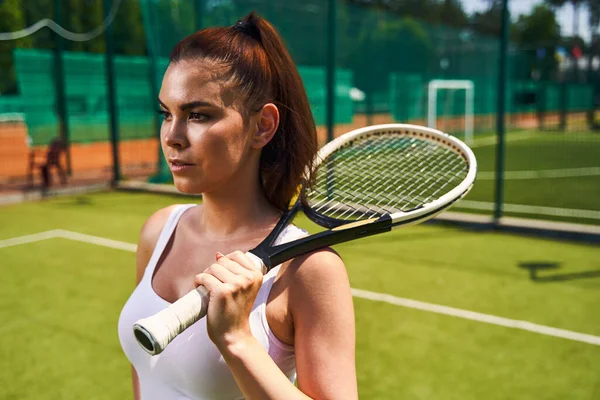 Penzitivní mladý sportovec stojící na tenisovém kurtu — Stock fotografie