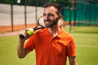 Tenis kortunda duran neşeli erkek oyuncu