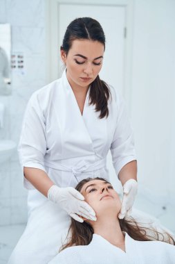 Uzman bir tıp çalışanı yüz masajını düzeltiyor.