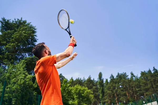 Sportivo caucasico che esegue un servizio di tennis in testa — Foto Stock