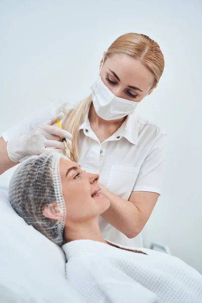 Positive delighted cosmetologist working with sterile instrument — Stockfoto