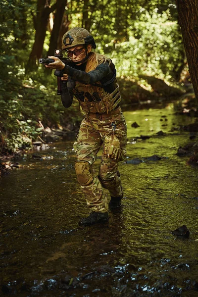 Woman in helmet standing in forest and holding gun in hands — Stock Photo, Image