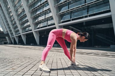 Kadın eğiliyor ve ellerini sol ayağa uzatıyor.