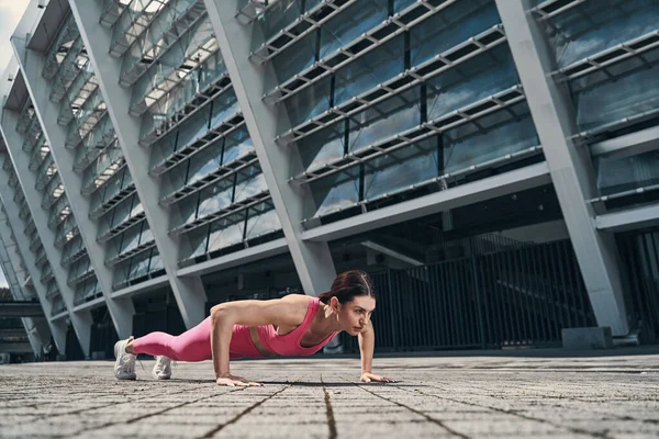 Mujer en ropa deportiva rosa haciendo flexiones al aire libre — Foto de Stock