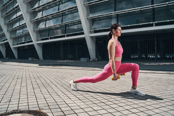 Atleta haciendo ejercicio con pesas en camino pavimentado — Foto de Stock