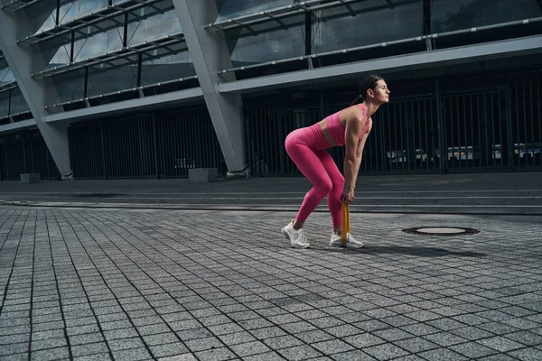 Pretty young woman outside pulling resistance band — Stock Photo, Image