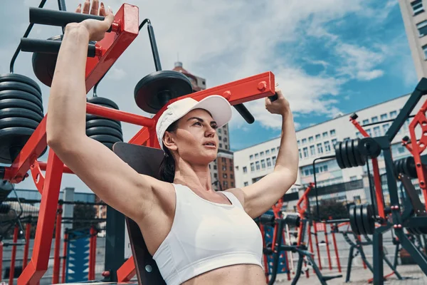 Mujer deportiva que toma asas de la máquina de ejercicio con agarre inverso — Foto de Stock