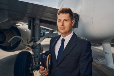 Serene lisanslı pilot bir uçağın yanında duruyor.