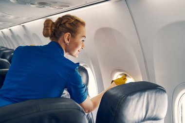 Gülümseyen hostes pencere perdesini kapatıyor.