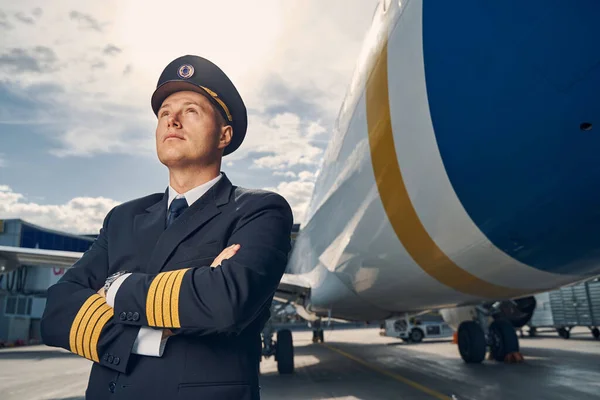 Piloto vestido de uniforme mirando al cielo — Foto de Stock