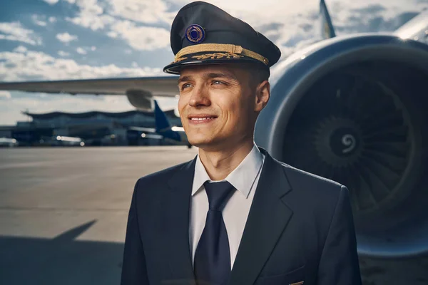 Sonriente piloto de aerolínea con una gorra mirando a la distancia — Foto de Stock