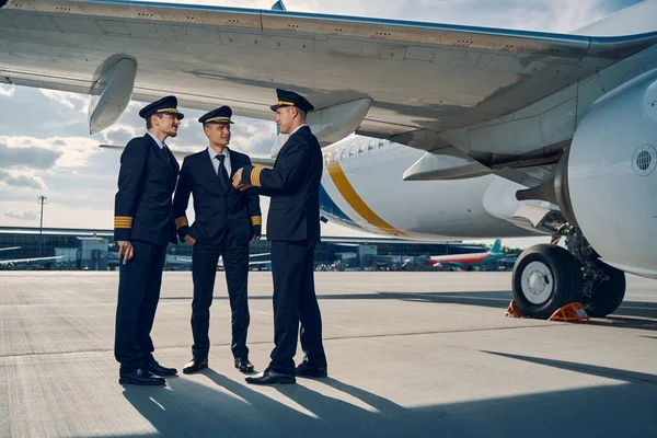 Tres aviadores conversando con un avión de tierra — Foto de Stock