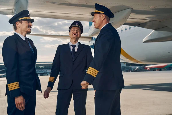 Три пилота авиакомпании наслаждаются друг другом — стоковое фото