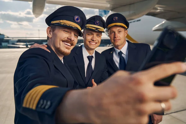 Tres aviadores en uniformes tomando selfies en el aeropuerto — Foto de Stock