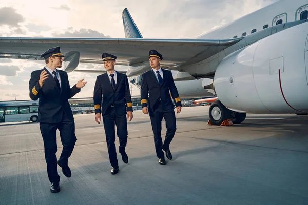 Three elegant aviators going along the runway — Stock Photo, Image