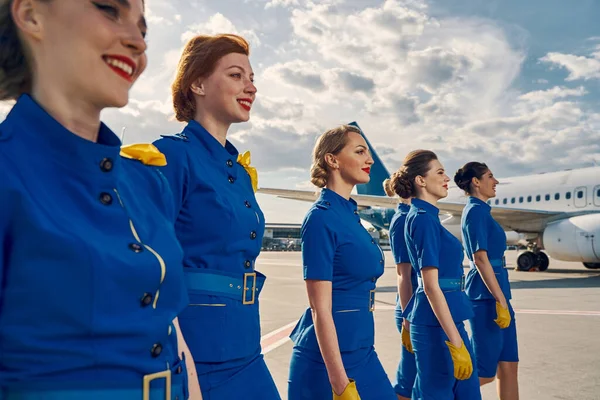 Beautiful joyous young air hostesses walking ahead — Stock Photo, Image