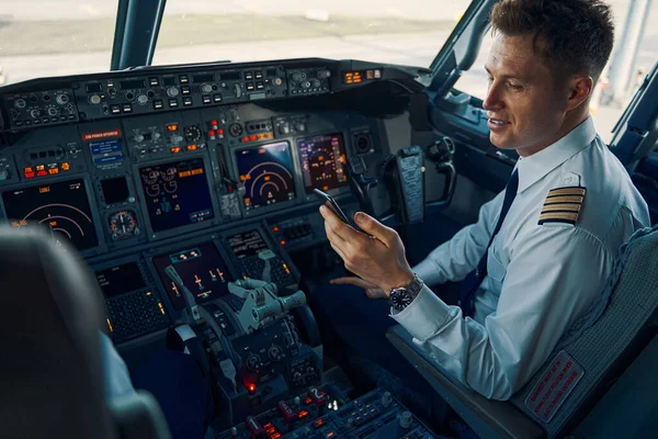 Glada flygare läser ett sms på sin smartphone — Stockfoto