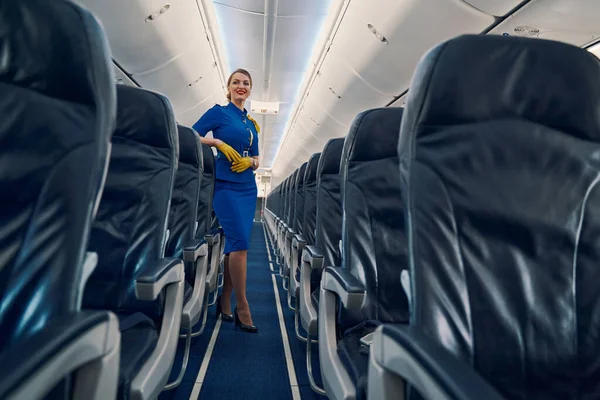 Счастливая привлекательная стюардесса, стоящая в салоне самолета — стоковое фото