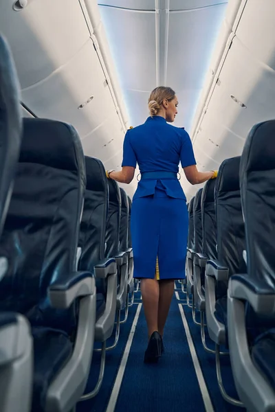Блондинка-стюардесса в форме, стоящая в салоне самолета. — стоковое фото